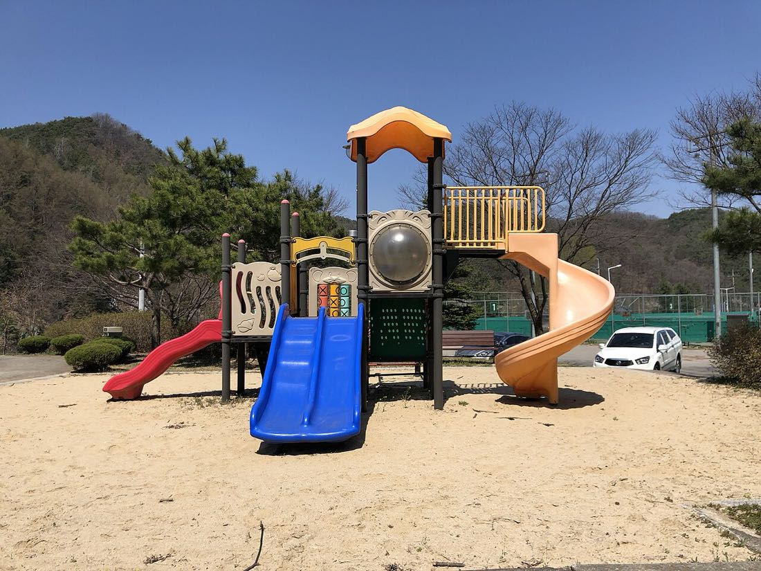 모래 바닥 위에 미끄럼틀이 달린 조합 놀이대가 있는 어린이공원